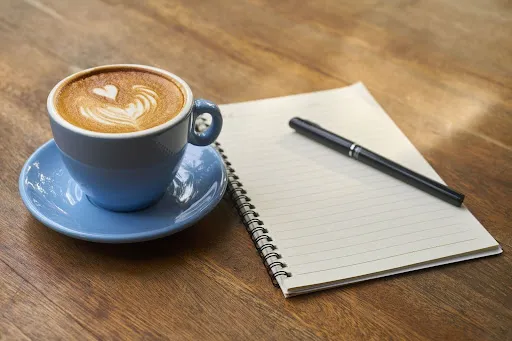 Coffee cup placed beside a notepad