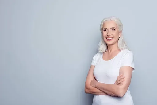 Older woman standing against light background